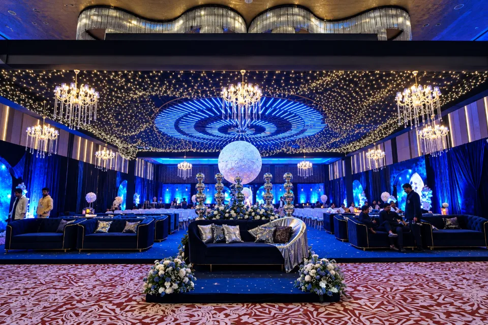 A ballroom washed in blue light under a starry canopy and crystal chandeliers, by Bluebird Events