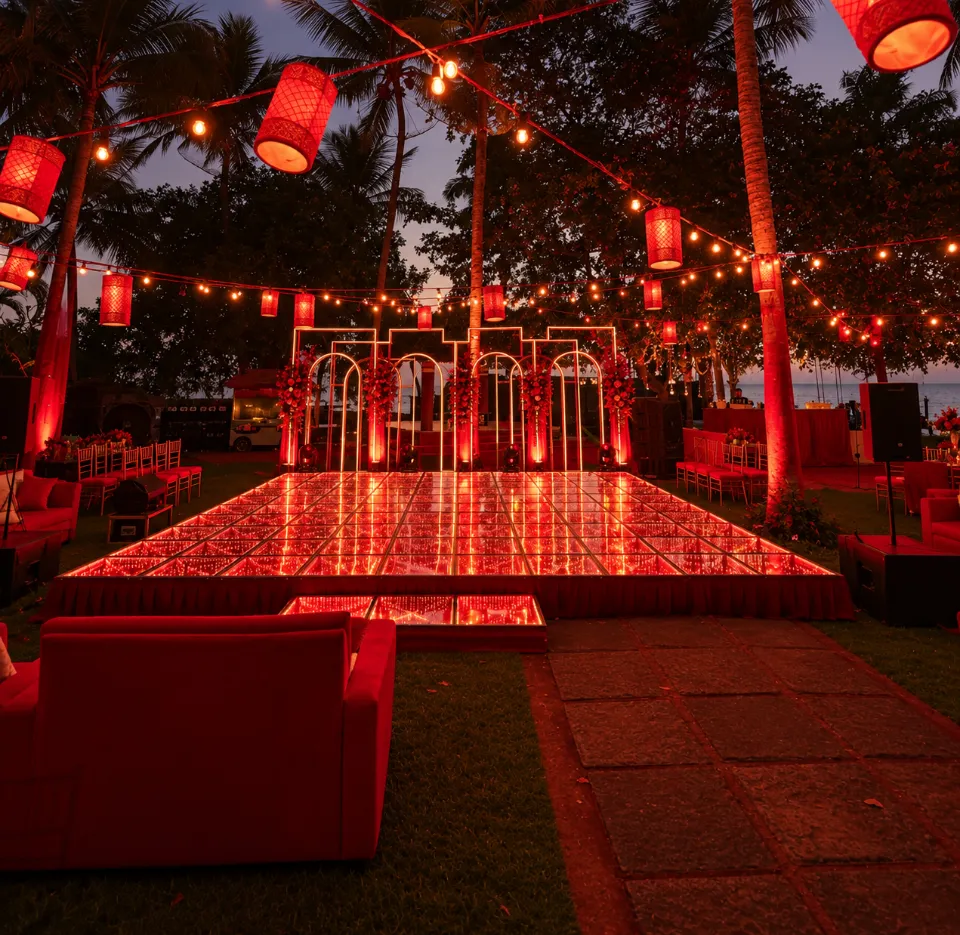 An LED dance floor glowing red under lanterns and string lights, set up by Bluebird Events