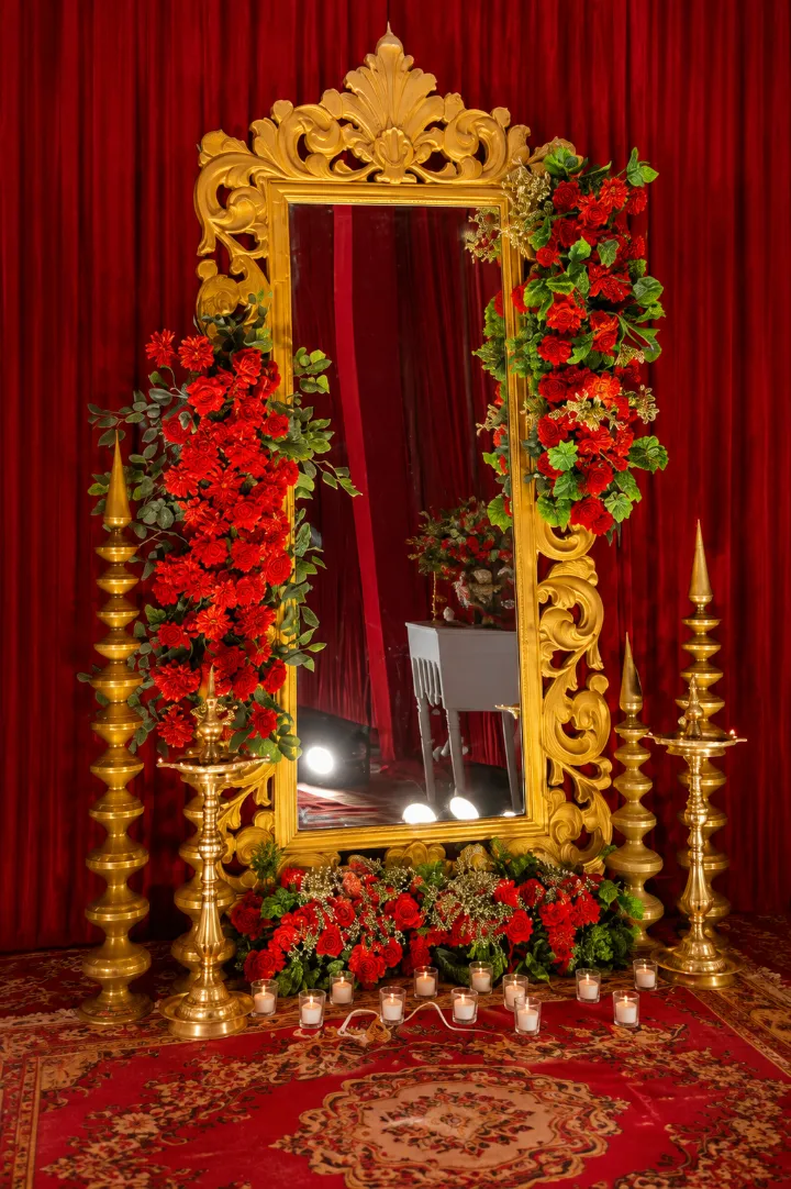 A red rose arch lined with candles and gold stands, decorated by Bluebird Events in Agra